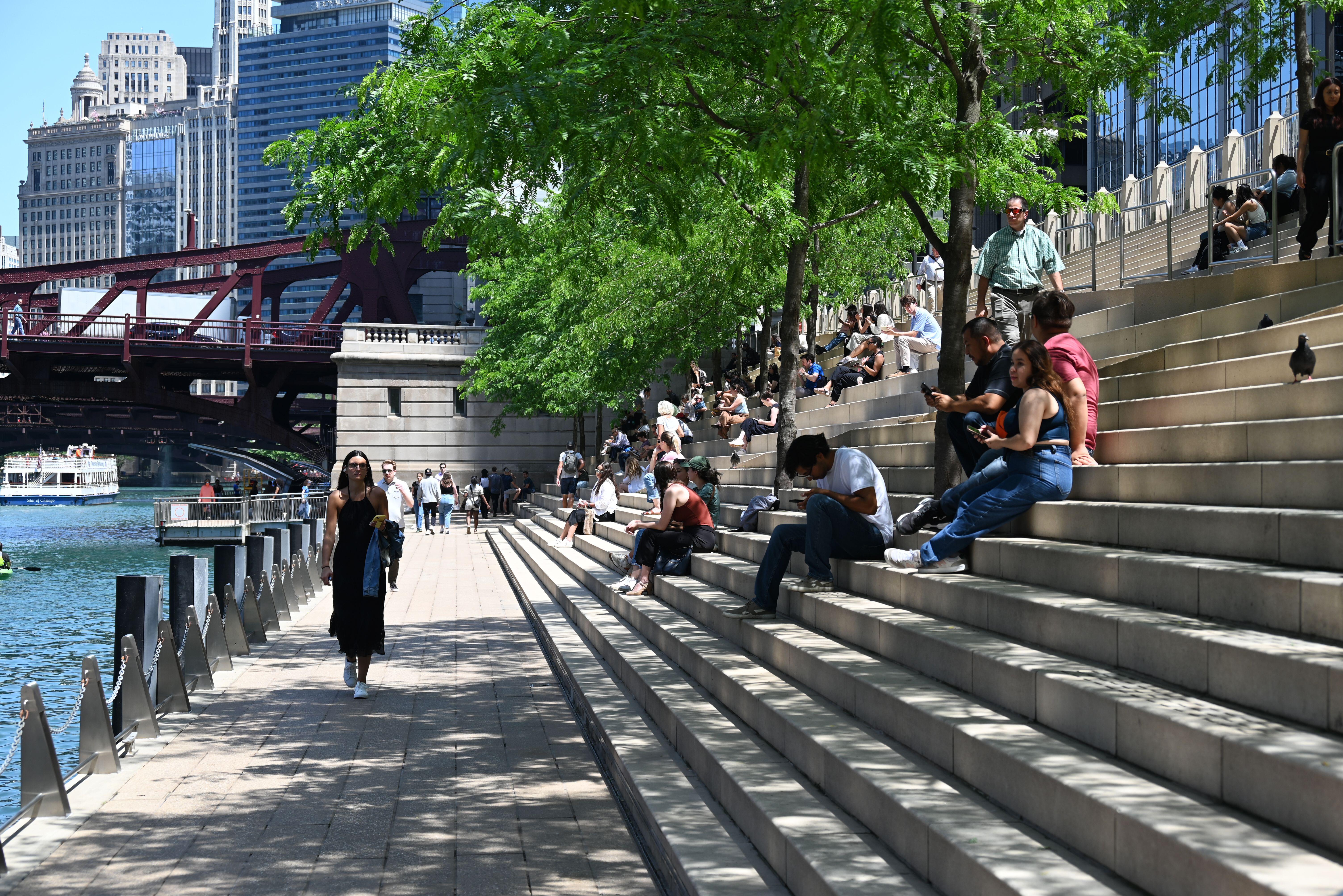 Chicagoans relax under the shade of trees on the steps of the Chicago Riverwalk.